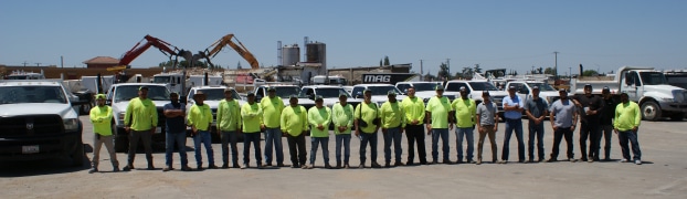A group of people in yellow vests, demonstrating their mag engineering skills, standing in front of trucks.