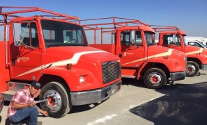 A fleet of red trucks parked in a parking lot.