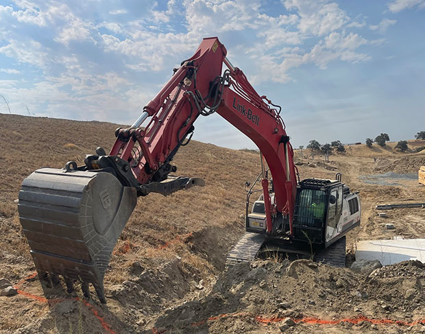 An excavator, operated by a skilled excavation contractor, diligently digs a hole in the dirt.