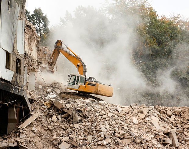 An excavator is demolishing a building and removing rubble.