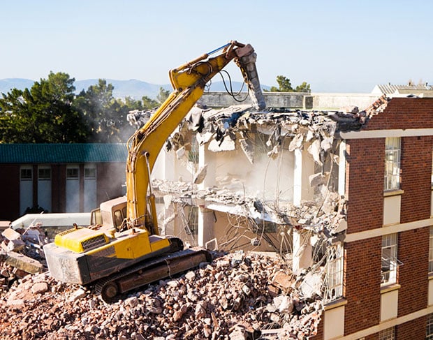 An excavator is being used by demolition contractors to demolish a building.