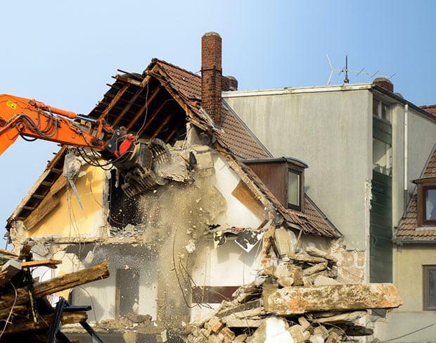Demolition contractors services utilizing an orange excavator for the demolition of a house.