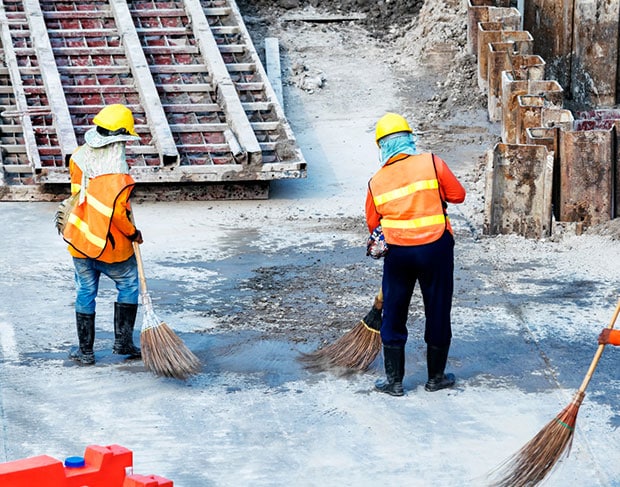 Three construction workers performing post construction clean up on a construction site.