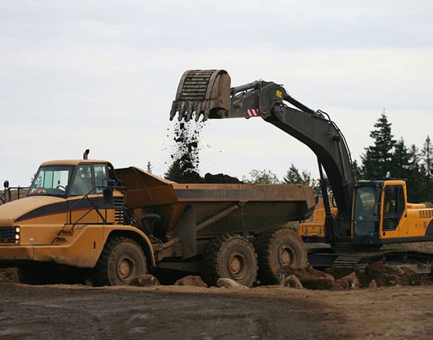 An excavator and a dump truck are utilized for efficient land clearing services.