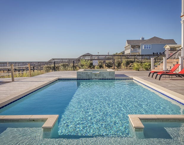 A pool with lounge chairs and a view of the ocean, now requiring pool demolition contractors for pool removal.