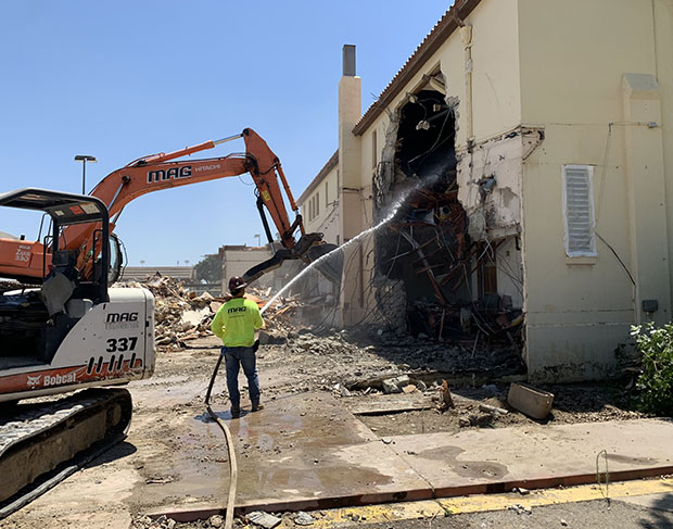 A building demolition contractors utilizing a bulldozer in front of it.
